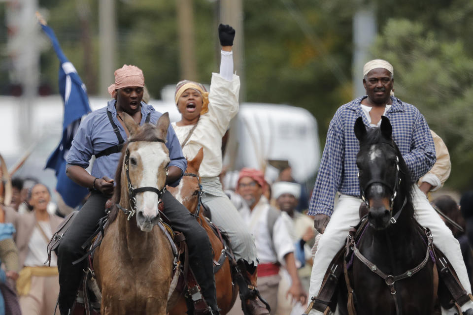 People participate in a performance artwork reenacting the largest slave rebellion in U.S. history in LaPlace, La., Friday, Nov. 8, 2019. The reenactment was conceived by Dread Scott, an artist who often tackles issues of racial oppression and injustice. Scott says that those who took part in the 1811 rebellion were "heroic" and that the rebellion is something that people should know about and be inspired by. (AP Photo/Gerald Herbert)