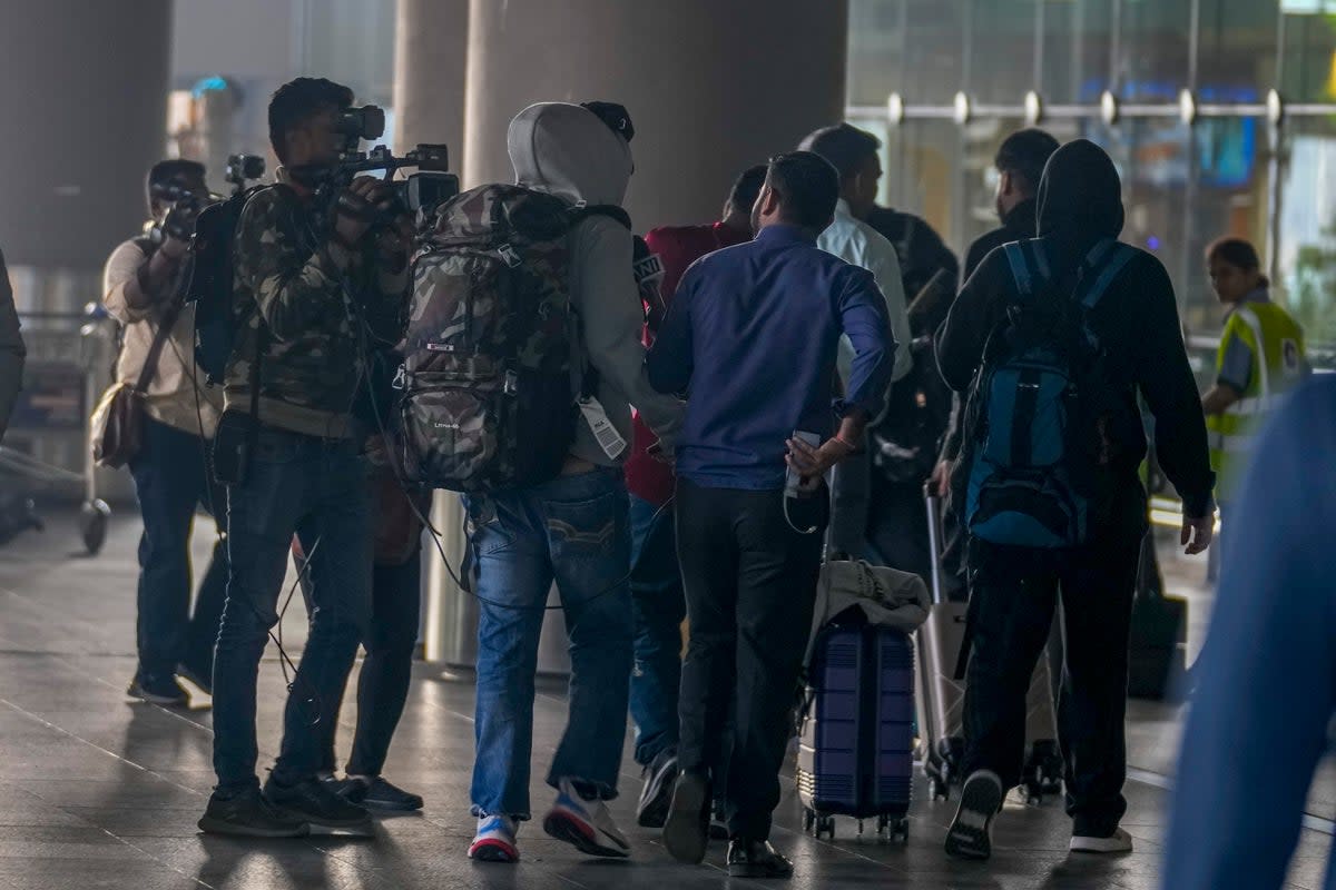 Journalists try to interview Indian passengers, who arrived in an unmarked Legend Airlines A340 from Vatry Airport (AP)
