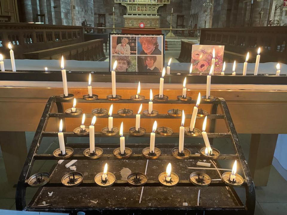 A photo of the four teenagers, Jevon Hirst, Harvey Owen, Wilf Fitchett and Hugo Morris, who died in a car crash in Snowdonia, North Wales, by candles and a sympathy card inside Shrewsbury Abbey (PA)