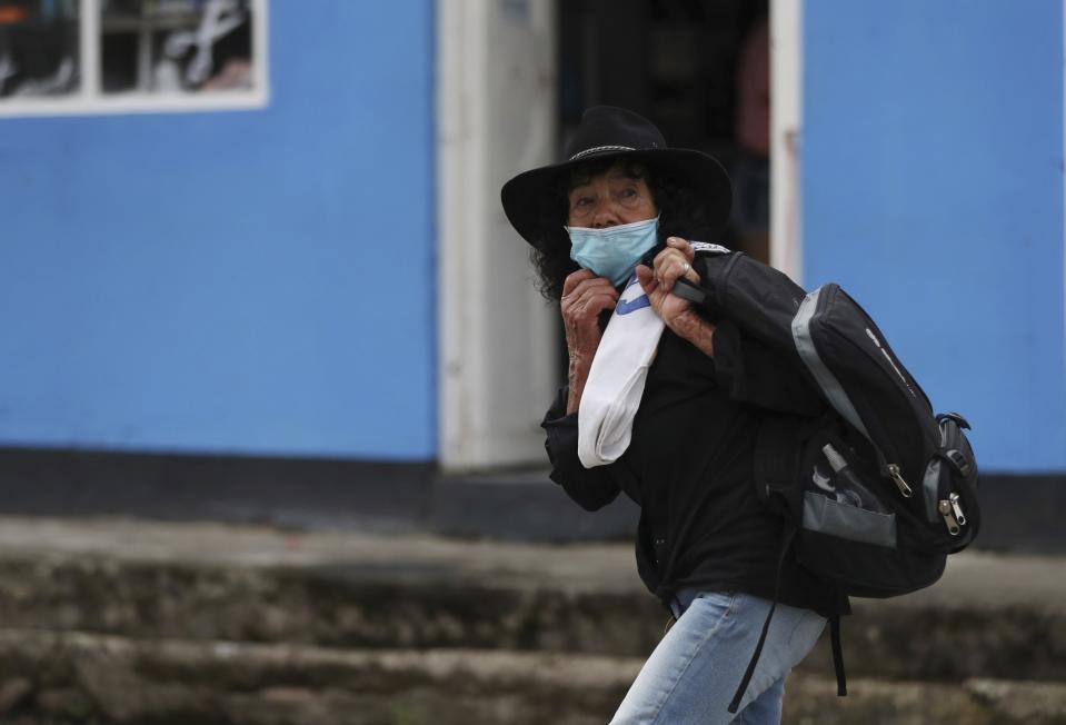 Wearing a mask to curb the spread of the new coronavirus, a woman walks in Campohermoso, Colombia, Thursday, March 18, 2021. According to the Health Ministry, Campohermoso is one of two municipalities in Colombia that has not had a single case of COVID-19 since the pandemic started one year ago. (AP Photo/Fernando Vergara)