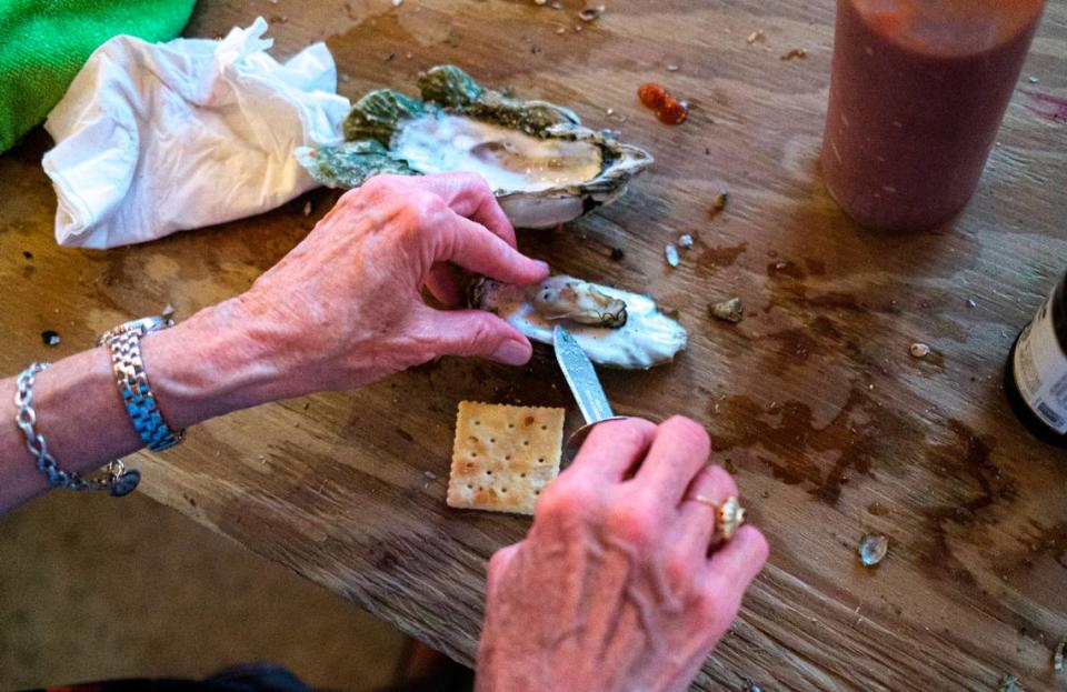 An oyster is carefully removed from it’s shell and placed on a saltine cracker with tobacso sauce, one of the many ways customers enjoy oysters at Bowen’s Island Restaurant. Bowen’s Island Restaurant hosts an oyster roast event for a wedding rehearsal party with some of the season’s first oysters from the Folly River near Charleston, S.C. Oct. 8, 2021.