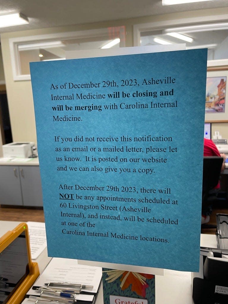 A note on the window at Asheville Internal Medicine informing patients about its upcoming merger with Carolina Internal Medicine.