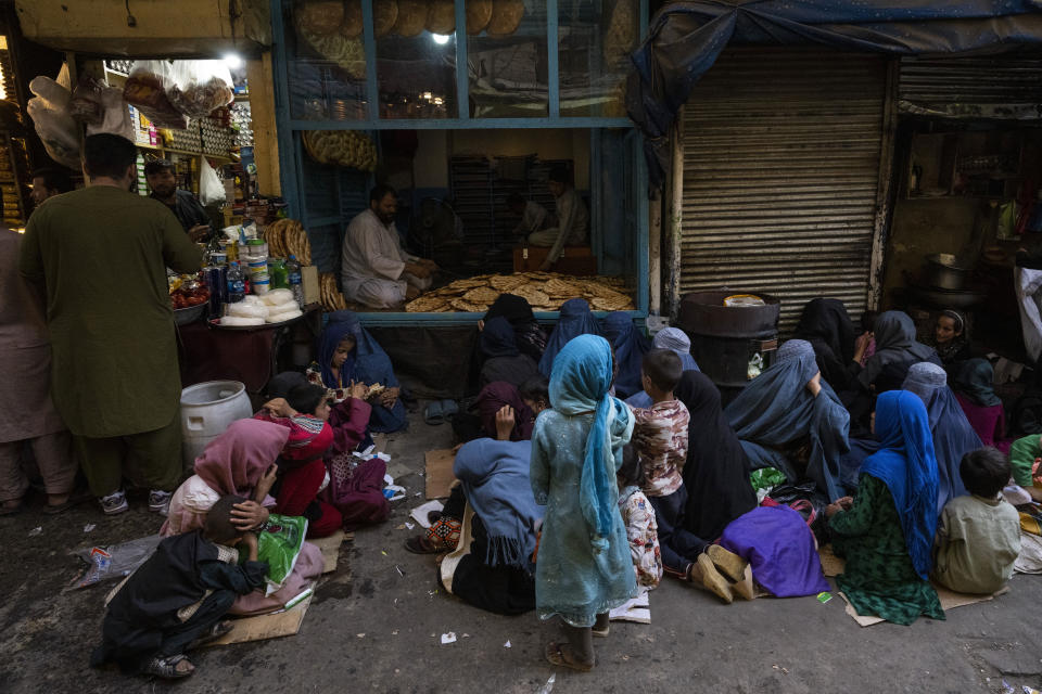 Afghan women and children sit in front of a bakery waiting for bread donations in Kabul's Old City, Afghanistan, Thursday, Sept. 16, 2021. (AP Photo/Bernat Armangue)