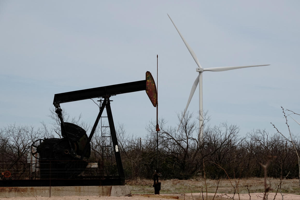 A pump jack drills oil crude from the Yates Oilfield in West Texas’s Permian Basin, as a 1.5MW GE wind turbine from the Desert Sky Wind Farm is seen in the distance, near Iraan, Texas, U.S., March 17, 2023. REUTERS/Bing Guan