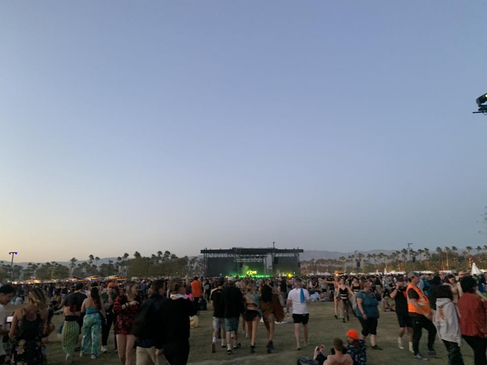 Crowds of people walking around with a stage in the background at Coachella