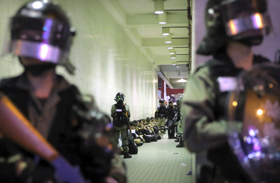 In this Saturday, Nov. 2, 2019, file photo, police in riot gear stand over people detained during a protest in Hong Kong. Hong Kong riot police fired multiple rounds of tear gas and used a water cannon Saturday to break up a rally by thousands of masked protesters demanding meaningful autonomy after Beijing indicated it could tighten its grip on the Chinese territory. (AP Photo/Kin Cheung, File)