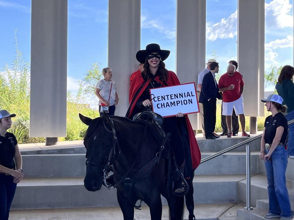 The 61st Masked Rider, Caroline Hobbs, posing with Centennial Champion at the Buddy Holly Hall. Centennial's name was announced by Texas Tech and United Supermarkets after a naming competition held in the summer.