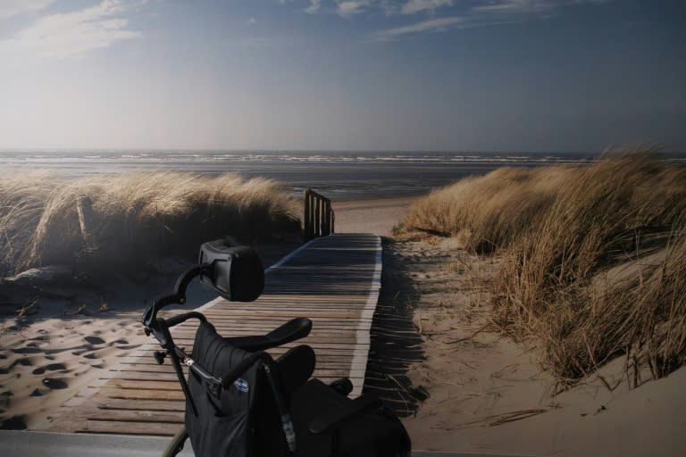 Liddy Imhof's empty wheelchair. Next to a wall in a hospital room depicting a seascape (Simon Wolfert)