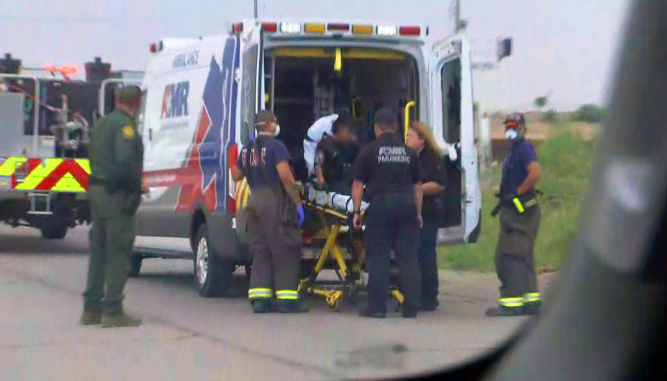 A young migrant woman is taken into an ambulance after suffering an apparent injury to her leg after falling from a nearby border wall in Sundland Park, N.M.  (NBC News)