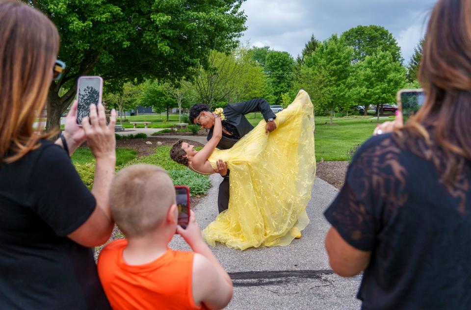 Family and friends take photos as Cade Thompson dips date Vivian Eagle at Friendship Gardens Park in Plainfield on Saturday, May 13, 2023, ahead of Avon's prom. Both Thompson and Eagle had and beat osteosarcoma, a cancer of the bone. The ribbon color of osteosarcoma is yellow.