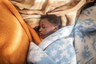 5-year old Timi sleeps between the blankets at her mother's feet, basking in the warmth of the sun's rays after being rescued in the Mediterranean Sea, international waters by the Spanish NGO Open Arms rescue vessel, Sunday, Feb. 14, 2021. Various African migrants drifting in the Mediterranean Sea after fleeing Libya on unseaworthy boats have been rescued. In recent days, the Libyans had already thwarted eight rescue attempts by the Open Arms, a Spanish NGO vessel, harassing and threatening its crew in international waters. Various African migrants drifting in the Mediterranean Sea after fleeing Libya on unseaworthy boats have been rescued. In recent days, the Libyans had already thwarted eight rescue attempts by the Open Arms, a Spanish NGO vessel, harassing and threatening its crew in international waters. (AP Photo/Bruno Thevenin)