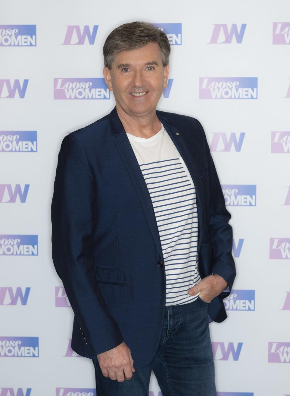 daniel o'donnell wearing a white striped tshirt with a navy blue blazer and jeans