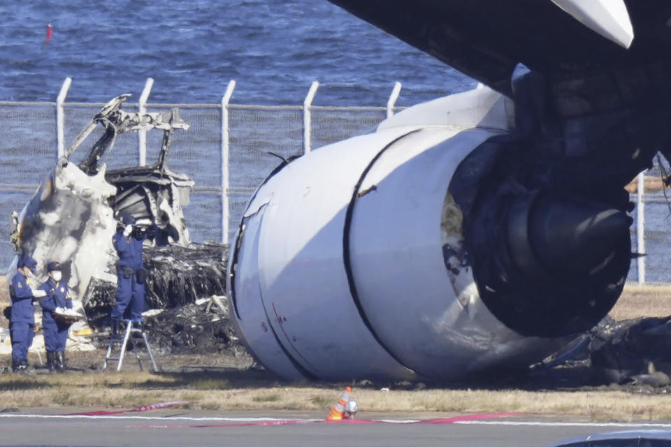 Police investigate the wreckage of Japan Airlines plane at Haneda airport on Thursday, Jan. 4, 2024, in Tokyo, Japan. A transcript of communication between traffic control and two aircraft that collided and burst into flames at Tokyo’s Haneda Airport showed that only the larger Japan Airlines passenger flight was given permission to use the runway where a coast guard plane was preparing for takeoff. (Kyodo News via AP)