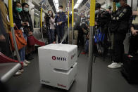 FILE - In this March 11, 2020, file photo, members of the media attend a news conference as a robot sprays hydrogen peroxide during a demonstration in a train carriage in Hong Kong. Mass transit systems around the world have taken unprecedented — and expensive — steps to curb the spread of the coronavirus, including testing powerful ultraviolet lamps to disinfect seats, poles and floors. (AP Photo/Kin Cheung, File)