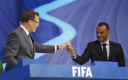 Former Brazilian player Cafu (R) hands a ball that he had drawn from a pot to FIFA Secretary General Jerome Valcke during the draw for the 2014 World Cup at the Costa do Sauipe resort in Sao Joao da Mata, Bahia state, December 6, 2013. REUTERS/Paulo Whitaker