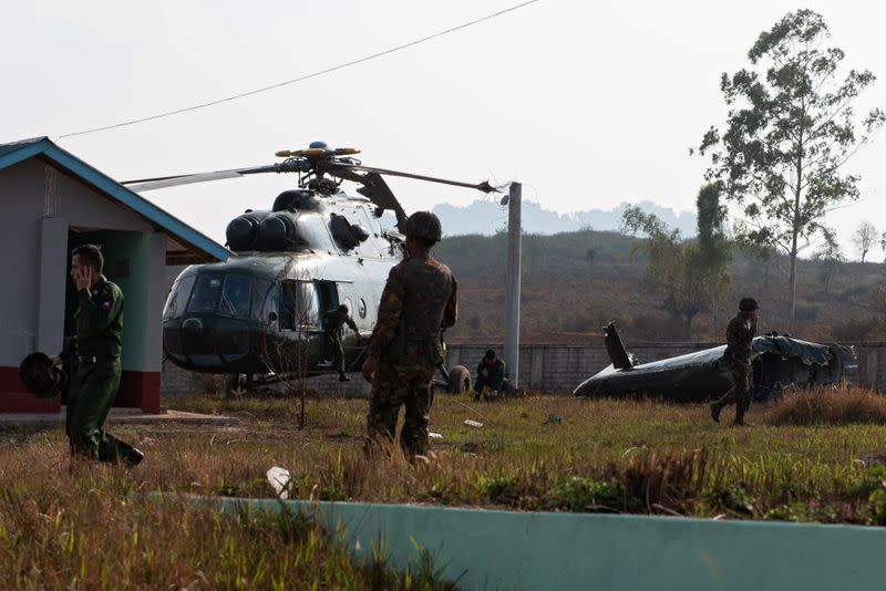 Soldiers exam a Myanmar military helicopter that had an accident while taking off from Lwe Khan