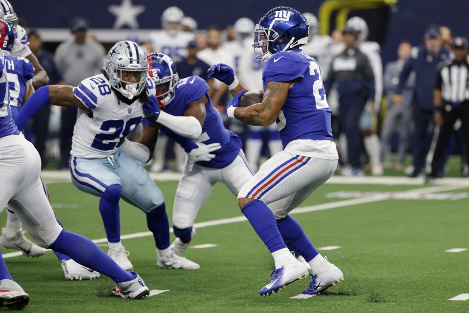 FILE - In this Sunday, Oct. 10, 2021, file photo, New York Giants running back Saquon Barkley (26) carries the ball as Dallas Cowboys safety Malik Hooker (28) rushes in during the first half of an NFL football game in Arlington, Texas. The talented fourth-year running back is probably going to miss at least a game or two after spraining his left ankle on a fluke play early in the Giants 44-20 loss to the Dallas Cowboys on Sunday. (AP Photo/Michael Ainsworth)