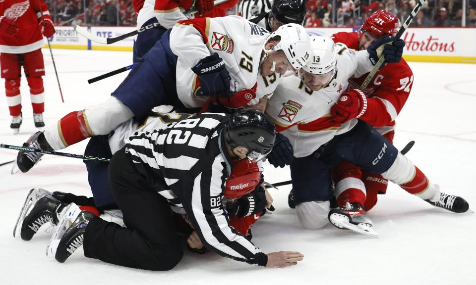 Linesman Ryan Galloway (82) tries to break up a fight between Florida Panthers left wing Matthew Tkachuk (19) and Detroit Red Wings defenseman Ben Chiarot, bottom, with Detroit Red Wings center Dylan Larkin (71) trying to pull center Sam Reinhart (13) off the pile, during the second period of an NHL hockey game Saturday, March 2, 2024, in Detroit. (AP Photo/Duane Burleson)