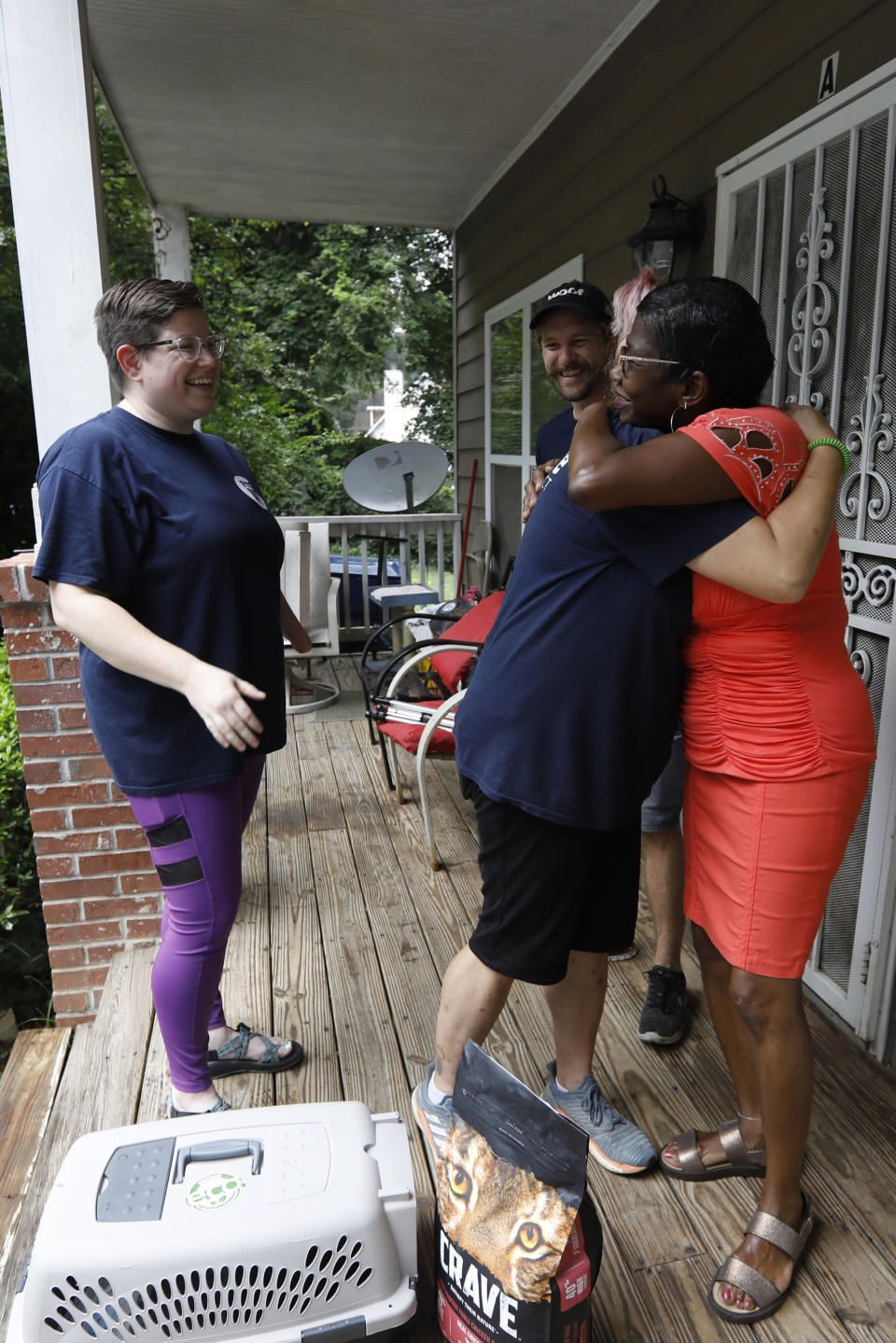 In this Tuesday, Aug. 27, 2019 photo, Carmen Webb-Davis hugs LifeLine Animal Project staff after they delivered free cat food and a crate to her home in Atlanta. Webb-Davis is a regular client of LifeLine Animal Project's Pets for Life program, which supports pet owners in underserved communities. Webb-Davis said the program helps relieve the financial burden of caring for her cats. (AP Photo/Andrea Smith)