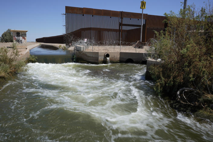 FILE - Water from the Colorado River flows in a canal along a border wall separating San Luis Rio Colorado, Mexico with San Luis, Arizona on Aug. 14, 2022, in San Luis Rio Colorado, Mexico. Exposed to the beating sun and hot dry air, more than 10% of the water carried by the Colorado River evaporates, leaks or spills as the 1,450-mile (2,334-kilometer) powerhouse of the West flows through the region’s dams, reservoirs and open-air canals. (AP Photo/Gregory Bull, File)