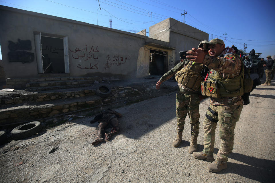 <p>Iraqi security forces pose for a picture next to a body in the village of al-Buseif, south of Mosul, during an offensive to retake the western side of the city from Islamic State (IS) group fighters on February 21, 2017. Iraqi forces consolidated positions after blasting their way to the southern edge of Mosul in an assault Baghdad and its partners hope will spell the doom of the jihadist “caliphate”. (Ahmad Al-Rubaye/AFP/Getty Images) </p>