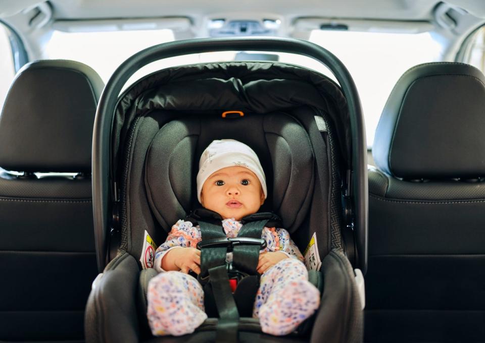 A baby in a rear-facing carseat in the backseat of a car.