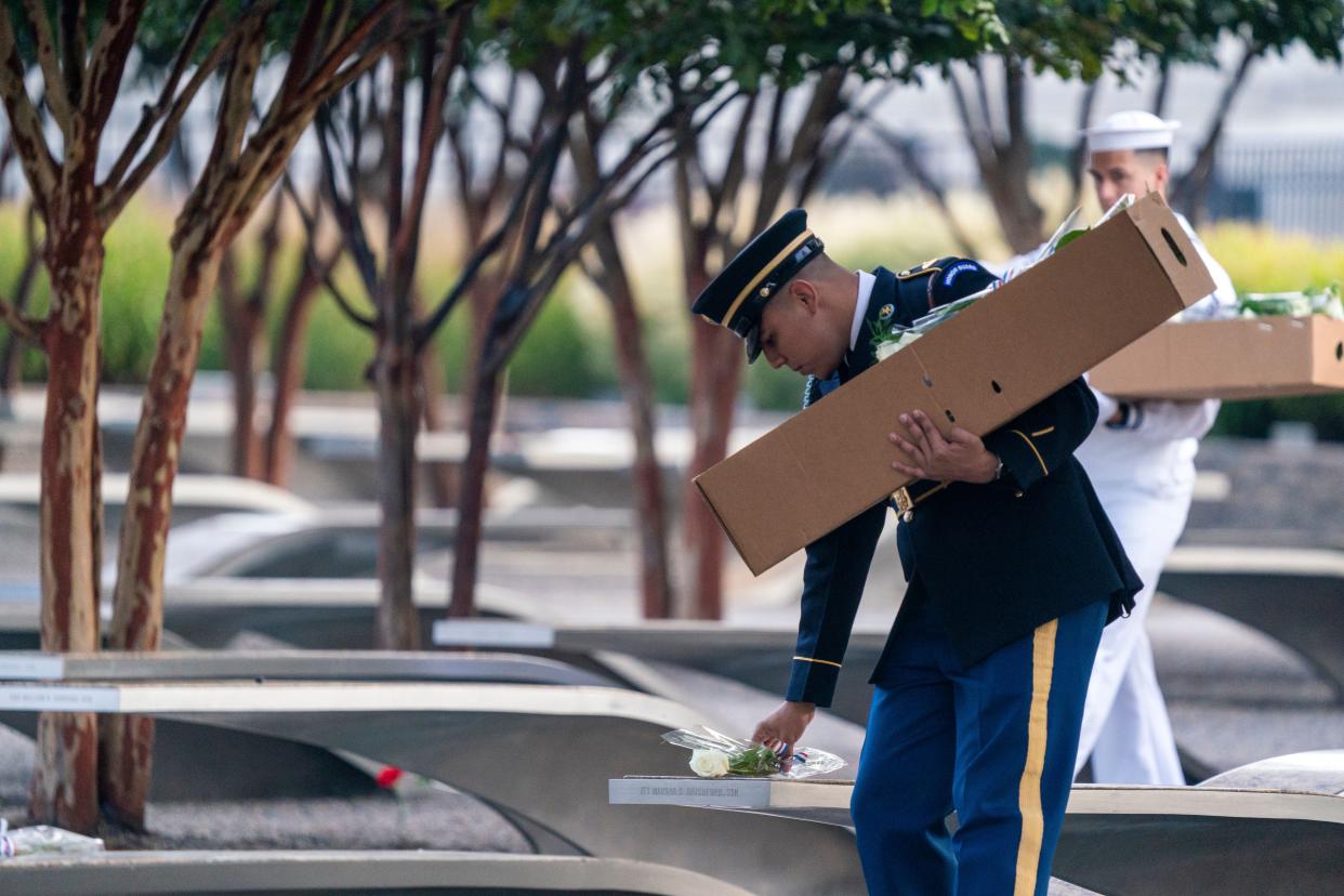 U.S. service members place roses on the memorial benches at the Pentagon 9/11 Memorial in Arlington, Va., on Wednesday.