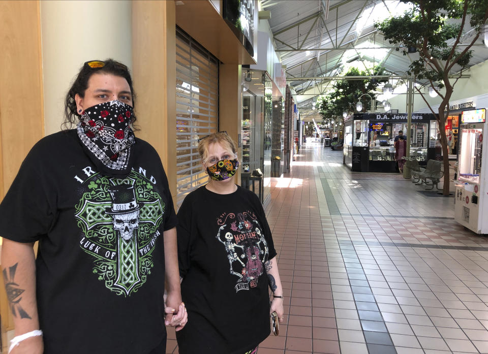 Bryan Gamez, left, and his wife, Billie Gamez, stand in the Yuba Sutter Mall in Yuba City, Calif., Thursday, July 9, 2020. Sutter County was one of the first counties to reopen its economy when it defied Gov. Gavin Newsom's stay-at-home order in May to allow restaurants, hair salons, gyms and shopping malls to reopen. But on Thursday, the county was added to the state watch list because of its rising number of coronavirus cases and hospitalizations. That will eventually trigger another round of restrictions, forcing bars to close and indoor operations to cease at restaurants and other public places for three weeks. Billie Gamez says she is frustrated at the prospect of more closings, saying "It's such a simple thing to keep your mask on, so why has it become such a huge thing?" (AP Photo/Adam Beam)