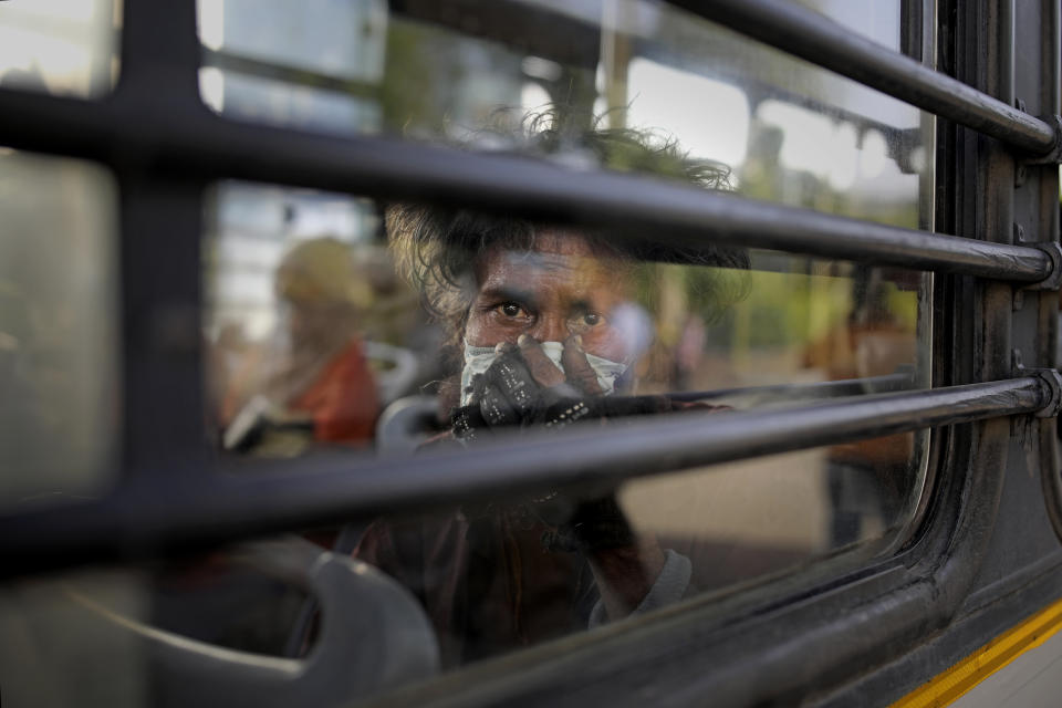 An Indian homeless man sits in a bus as he is being evicted with other homeless people and migrant laborers from the banks of Yamuna River where they have been squatting during the coronavirus lockdown in New Delhi, India, April 15, 2020. (AP Photo/Altaf Qadri)