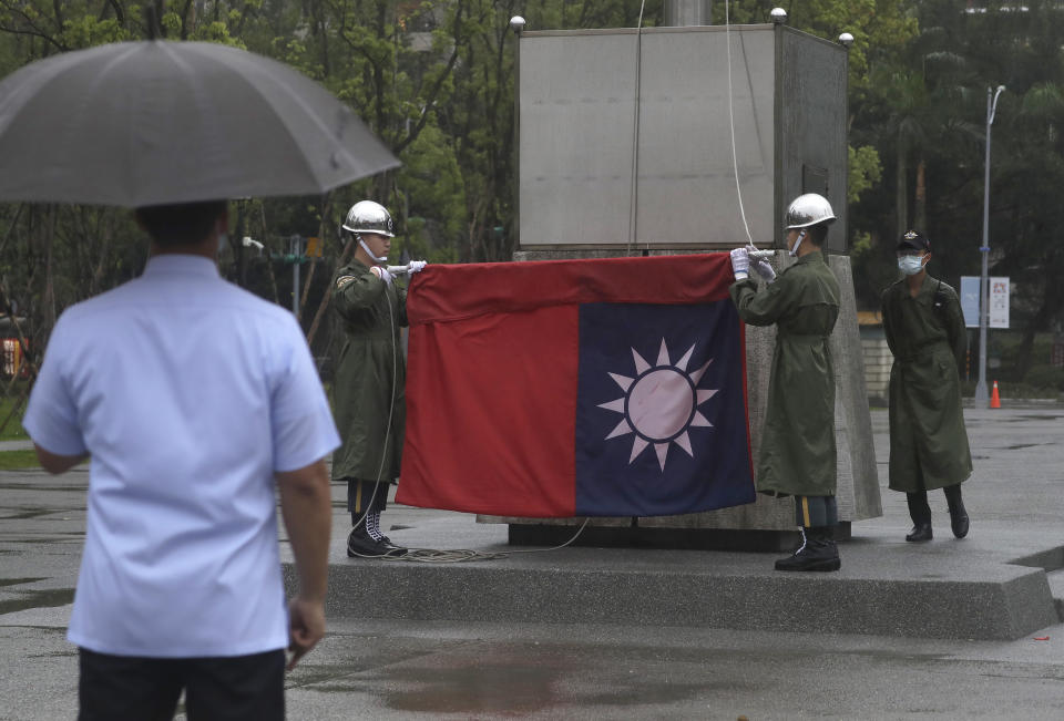 FILE - Two soldiers fold the national flag during the daily flag ceremony at the National Dr. Sun Yat-Sen Memorial Hall in Taipei, Taiwan, on May 7, 2023. Taiwan’s government is racing to counter China’s military, but many on the island say they don’t share the sense of threat. (AP Photo/Chiang Ying-ying, File)