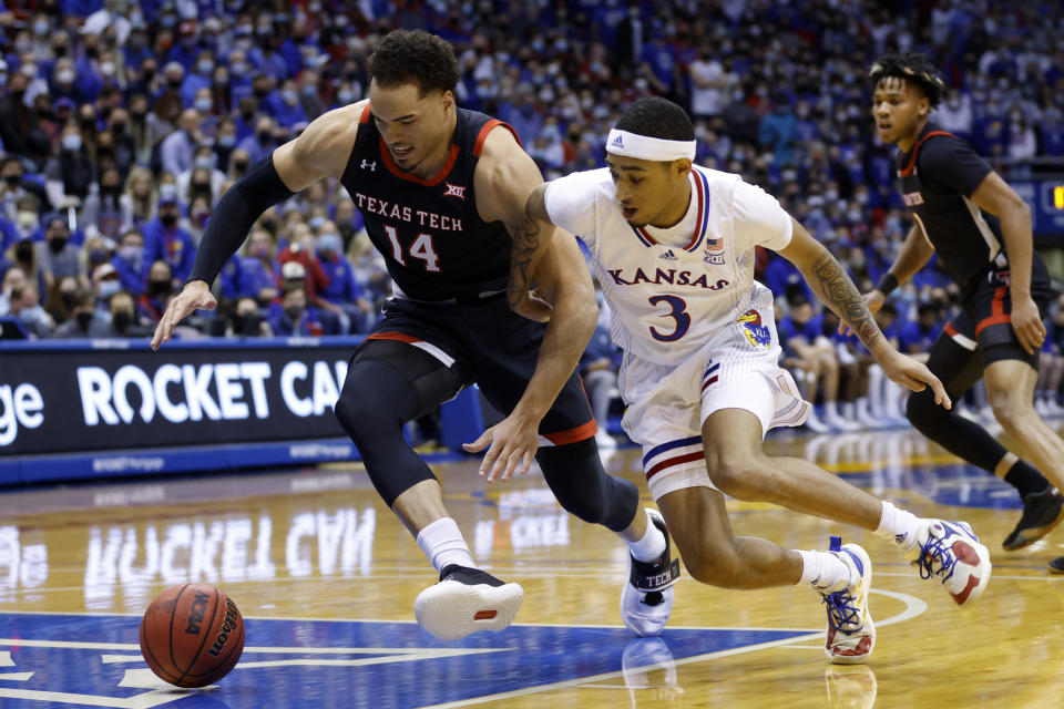 Texas Tech forward Marcus Santos-Silva (14) and Kansas guard Dajuan Harris Jr. (3) go after the ball during the first half of an NCAA college basketball game on Monday, Jan. 24, 2022 in Lawrence, Kan. (AP Photo/Colin E. Braley)