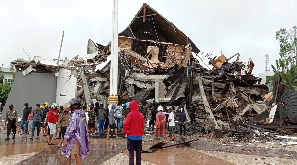 <p>People look at the damaged province’s office of governor of West Sulawesi following an earthquake in Mamuju</p> (Reuters)