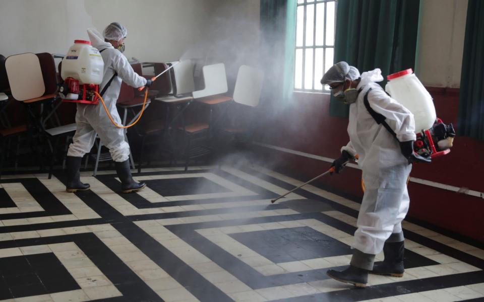 Workers sanitise a polling station, the day ahead of the first round of presidential and parliamentary elections - Reuters