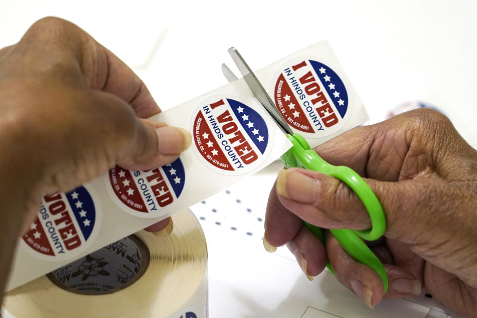 FILE - A precinct worker in Jackson, Miss., cuts individual "I Voted in Hinds County" stickers from the roll, Aug. 8, 2023. Super Tuesday put former President Donald Trump within reach of clinching his third consecutive Republican presidential nomination. But it may be Republican voters in Georgia, Hawaii, Mississippi and Washington who put him over the top. President Joe Biden is also competing in presidential contests that day, but the earliest he can clinch his party's nomination is a week later on March 19. (AP Photo/Rogelio V. Solis, File)