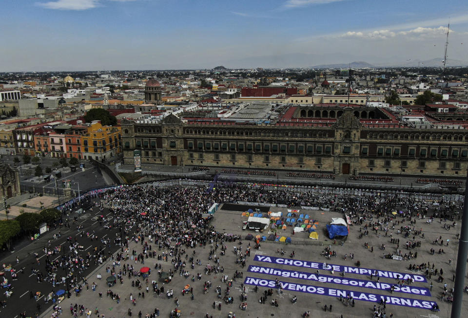 People protest around Mexico's Presidential Palace during a march to commemorate International Women's Day in Mexico City, Monday, March 8, 2021. The banners on the ground of the plaza read in Spanish "No more impunity," #No aggressor to power," "See you at the polls." (AP Photo/Fernando Llano)