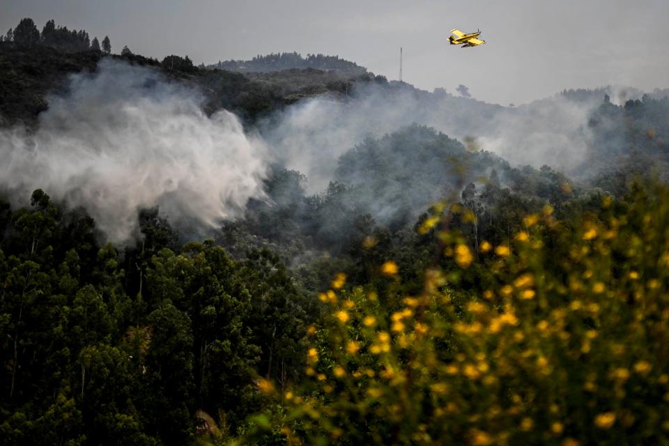 TOPSHOT - A firefighter aircraft Air Tractor AT-802F Fire Boss drops water in a wildfire near Bustelo, east of Amarante, north of Portugal, on July 16, 2022. (Photo by PATRICIA DE MELO MOREIRA / AFP) (Photo by PATRICIA DE MELO MOREIRA/AFP via Getty Images)