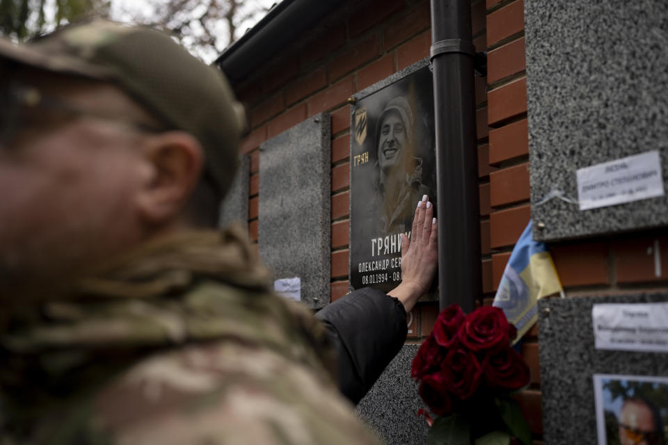 A woman pays her last respect to Ukrainian soldier Oleksandr Hrianyk in Kyiv, Ukraine, Saturday, Oct. 28, 2023. Hrianyk died in battle in May 2022 in the city of Mariupol, but was only cremated recently after his remains were found and identified. (AP Photo/Bram Janssen)