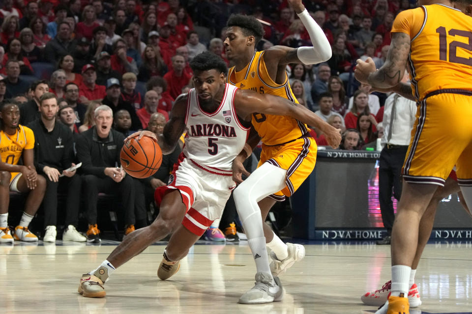 Arizona guard KJ Lewis (5) drives past Arizona State forward Alonzo Gaffney (8) during the first half of an NCAA college basketball game, Saturday, Feb. 17, 2024, in Tucson, Ariz. (AP Photo/Rick Scuteri)