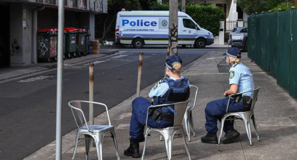 NSW police officers wearing face masks guard the entrance of the Urban Newtown hotel. Australian travellers were quarantined inside.