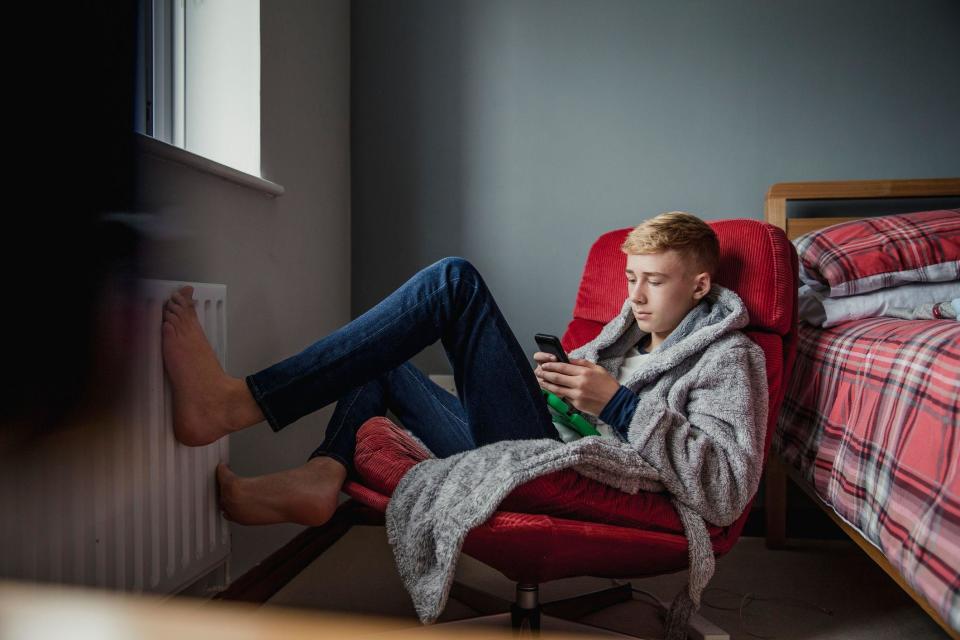 Un chico en su cuarto viendo su teléfono