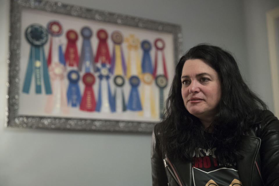 In this Thursday, Jan. 31, 2019, photo Lisa Topol is seen near ribbons won in competition by her rescue dog Schmutzy in New York. Topol recently had the DNA tested on her mixed-breed dogs, Plop and Schmutzy. Genetic testing for dogs has grown rapidly in recent years, fueled by companies marketing kits that offer to decode dogs’ heritage and health as simply, or laboriously, as owners can swab a canine cheek. (AP Photo/Mary Altaffer)