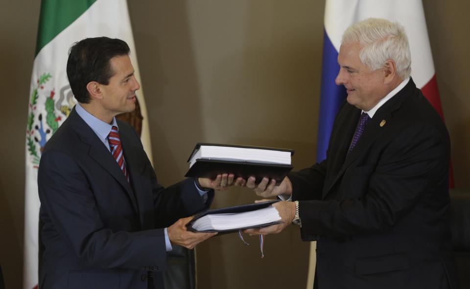 Mexico's President Enrique Pena Nieto, left, and Panama's President Ricardo Martinelli exchange documents after signing a Free Trade Agreement between both countries during the last day of the World Economic Forum on Latin America in Panama City, Panama, Thursday, April 3, 2014. (AP Photo/Arnulfo Franco)