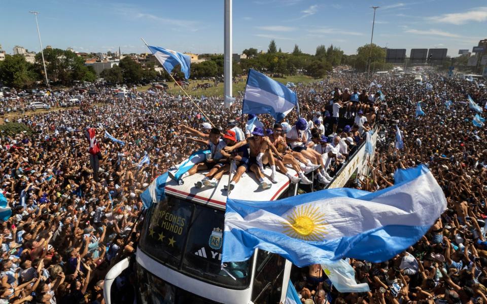 El equipo argentino de fútbol que ganó el título de la Copa del Mundo viaja en la parte superior de un autobús abierto durante su desfile de bienvenida en Buenos Aires - AP