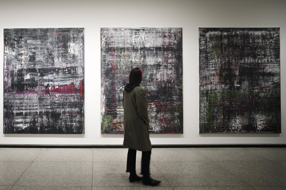 A woman walks in front of the 'Birkenau' paintings in a new exhibition with art works of German artist Gerhard Richter at the New National Gallery in Berlin, Germany, Friday, March 31, 2023. Richter's foundation gave on permanent loan 100 works of the artist to the New National Gallery where they will be shown in the permanent exhibition. (AP Photo/Markus Schreiber)