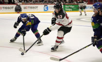 Kent Johnson of Canada, center, is challenged by Italy's Alex Petan during the group A Hockey World Championship match between Italy and Canada in Helsinki, Finland, Sunday May 15, 2022. (AP Photo/Martin Meissner)