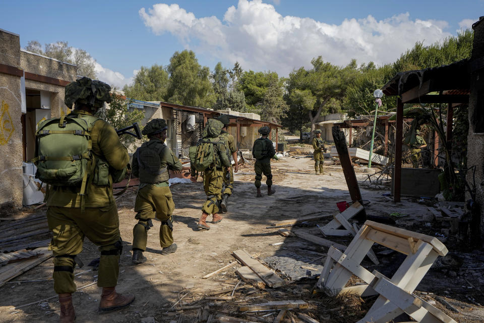 Israeli soldiers patrol next to houses damaged by Hamas militants in Kibbutz Kfar Azza, Israel, Wednesday, Oct. 18, 2023. The Kibbutz was overrun by Hamas militants from the nearby Gaza Strip on Oct. 7, when they killed and captured many Israelis. (AP Photo/Ariel Schalit)