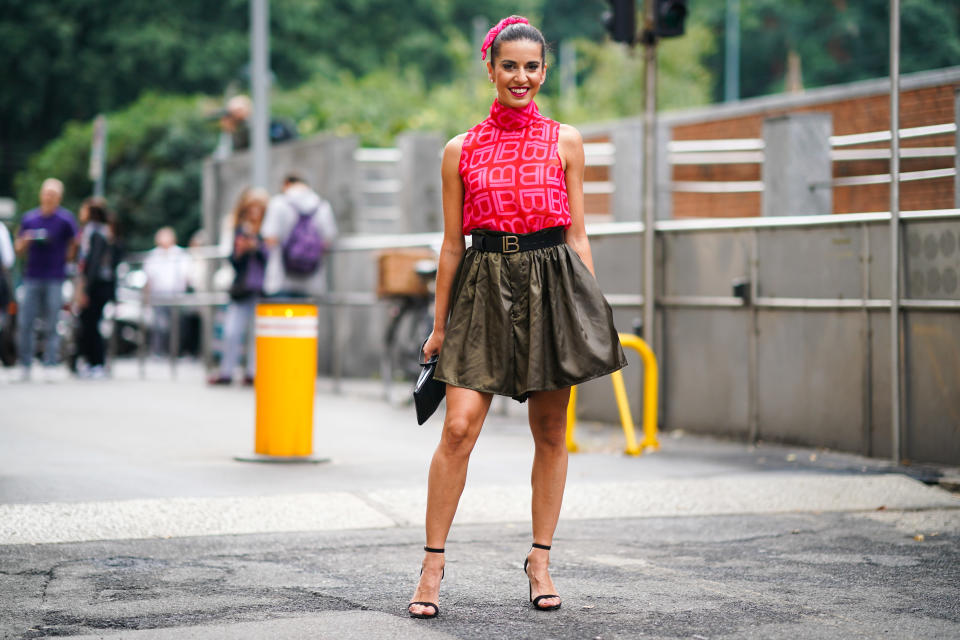 MILAN, ITALY - SEPTEMBER 22:  A guest wears a pink headband, a sleeveless turtleneck pink top with printed "B", a belt, a pleated skirt, heels shoes, outside the Laura Biagiotti show during Milan Fashion Week Spring/Summer 2020 on September 22, 2019 in Milan, Italy. (Photo by Edward Berthelot/Getty Images)