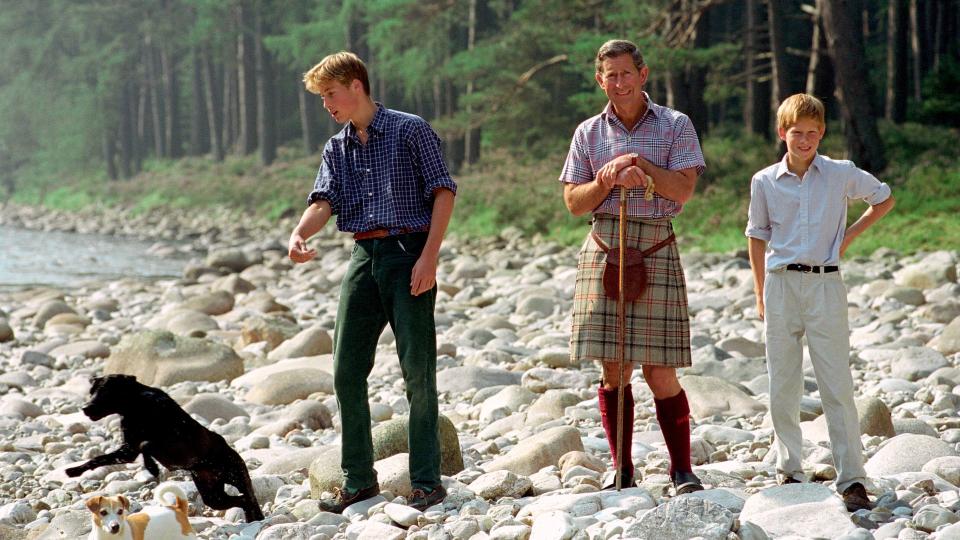 Then-Prince Charles In Kilt And Sporran And Shepherd's Crook Walking Stick With Prince William & Prince Harry At Polvier, By The River Dee, Balmoral Castle Estate in August 1997