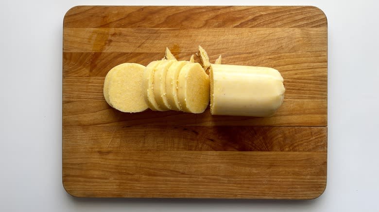 a tube of polenta sliced on a cutting board
