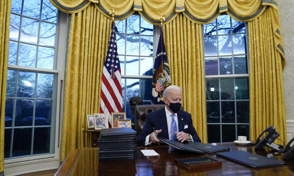 Joe Biden signs his first executive orders in the Oval Office of the White House on 20 January.